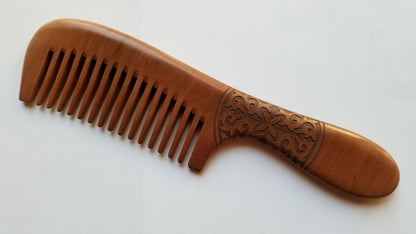 Long-handle wood comb for women — Celtic spiral vine carving on warm peach wood, flat lay — Arakicrafts