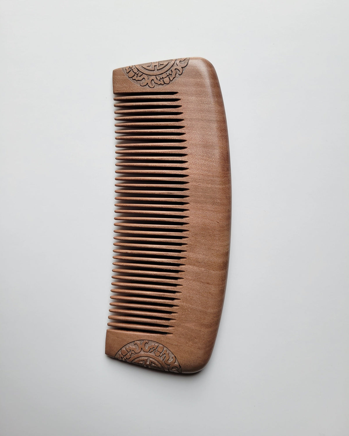 a peach wood comb showing fine grain, soft brown tones, and a gently curved outline