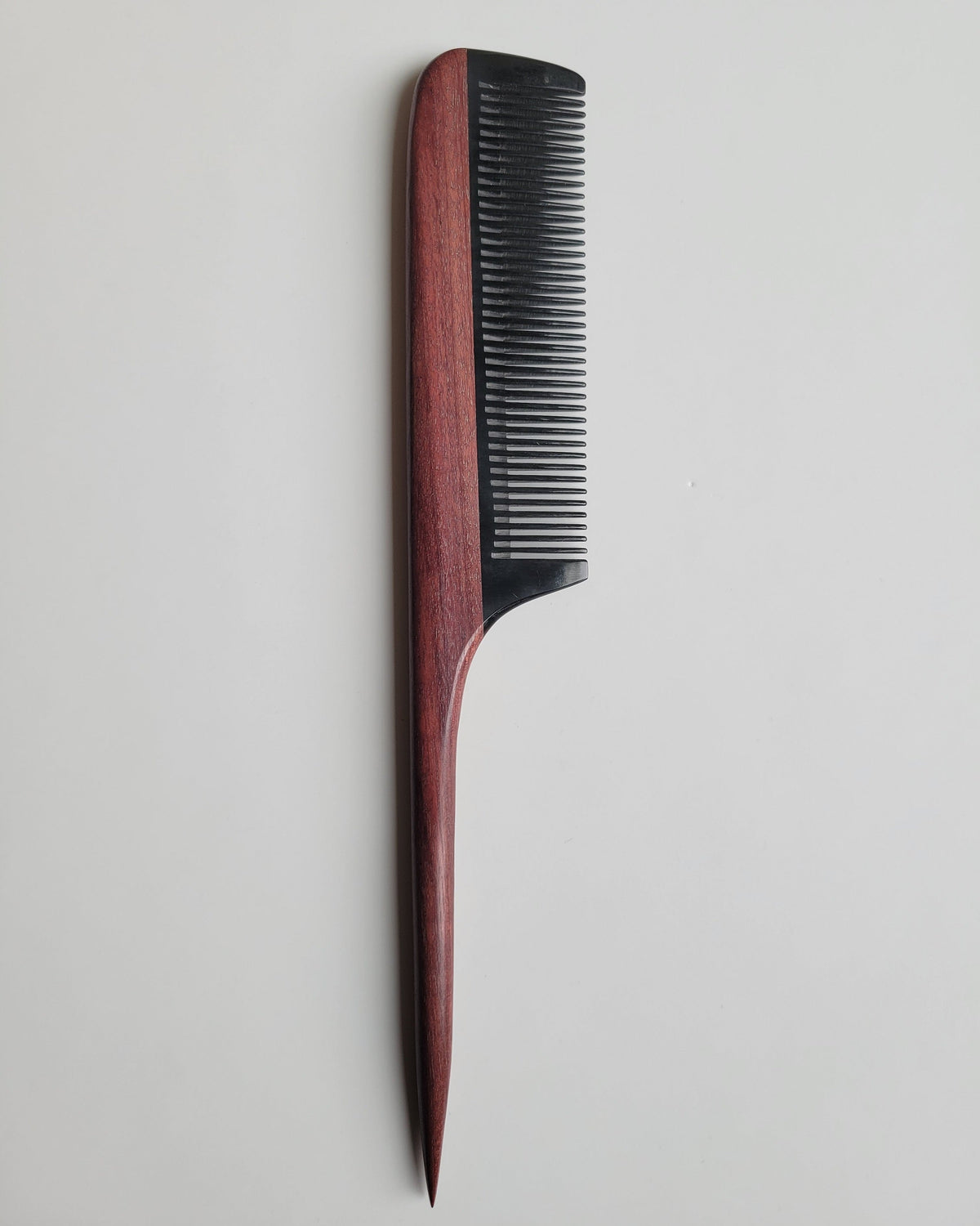 Hand-inlaid rat tail comb in purple heart wood and buffalo horn, reddish-brown jewel-toned handle with jet-black fine teeth