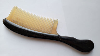A hand inlayed African Ebony and ram horn comb with a long curved handle.  it has fine teeth and comes with a fabric gift bag.