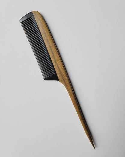 Green sandalwood rat tail comb flat lay, olive-toned hardwood grain with black buffalo horn fine teeth, aromatic wood hair comb