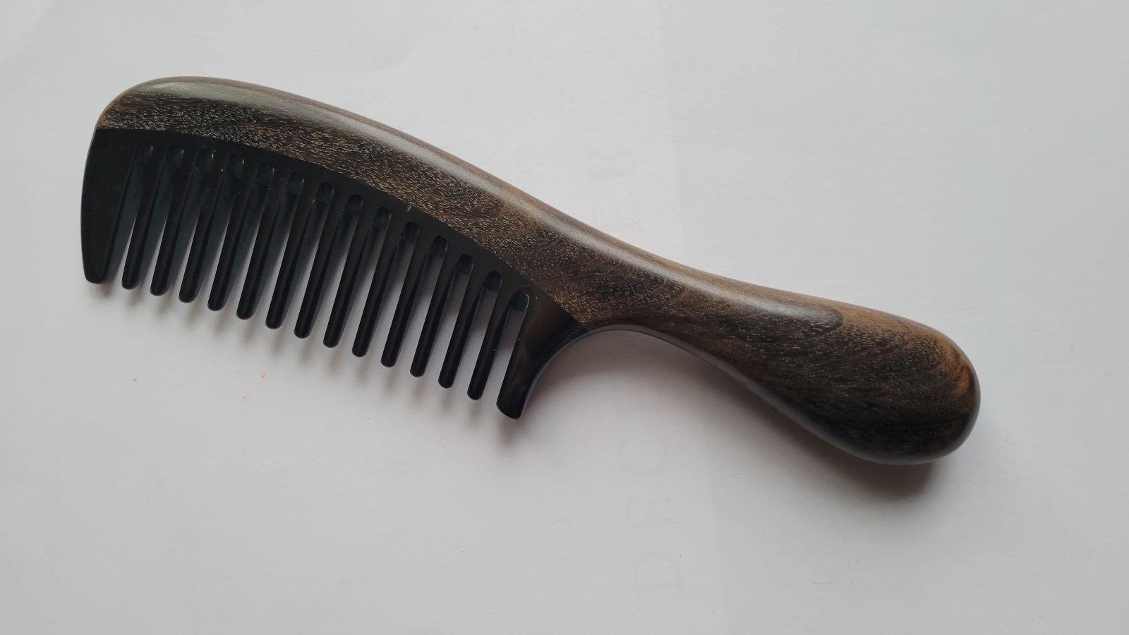 Wide-tooth wood and horn comb — overhead flat lay showing even tooth spacing and natural wood grain detail
