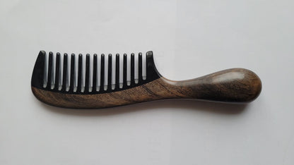 Chacate Preto wood comb with hand-inlaid black buffalo horn teeth — angled flat lay highlighting dark grey wood tone