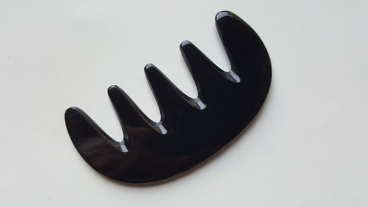 Near-black yak horn five-tooth comb, flat lay overhead showing pale streaks through dark horn grain — Arakicrafts