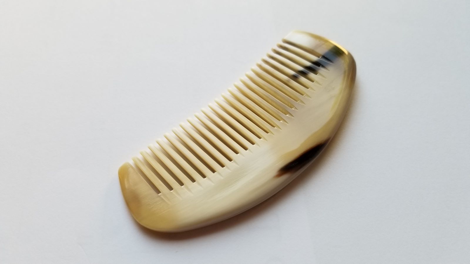 Petite yak horn comb, pale cream horn with dark amber natural stripe, crescent half-moon silhouette, pocket-sized fine tooth comb