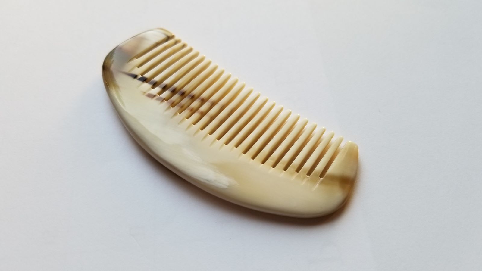 Yak horn pocket comb back view, natural dark amber stripe marking on pale cream horn, anti-static keratin-rich fine tooth comb
