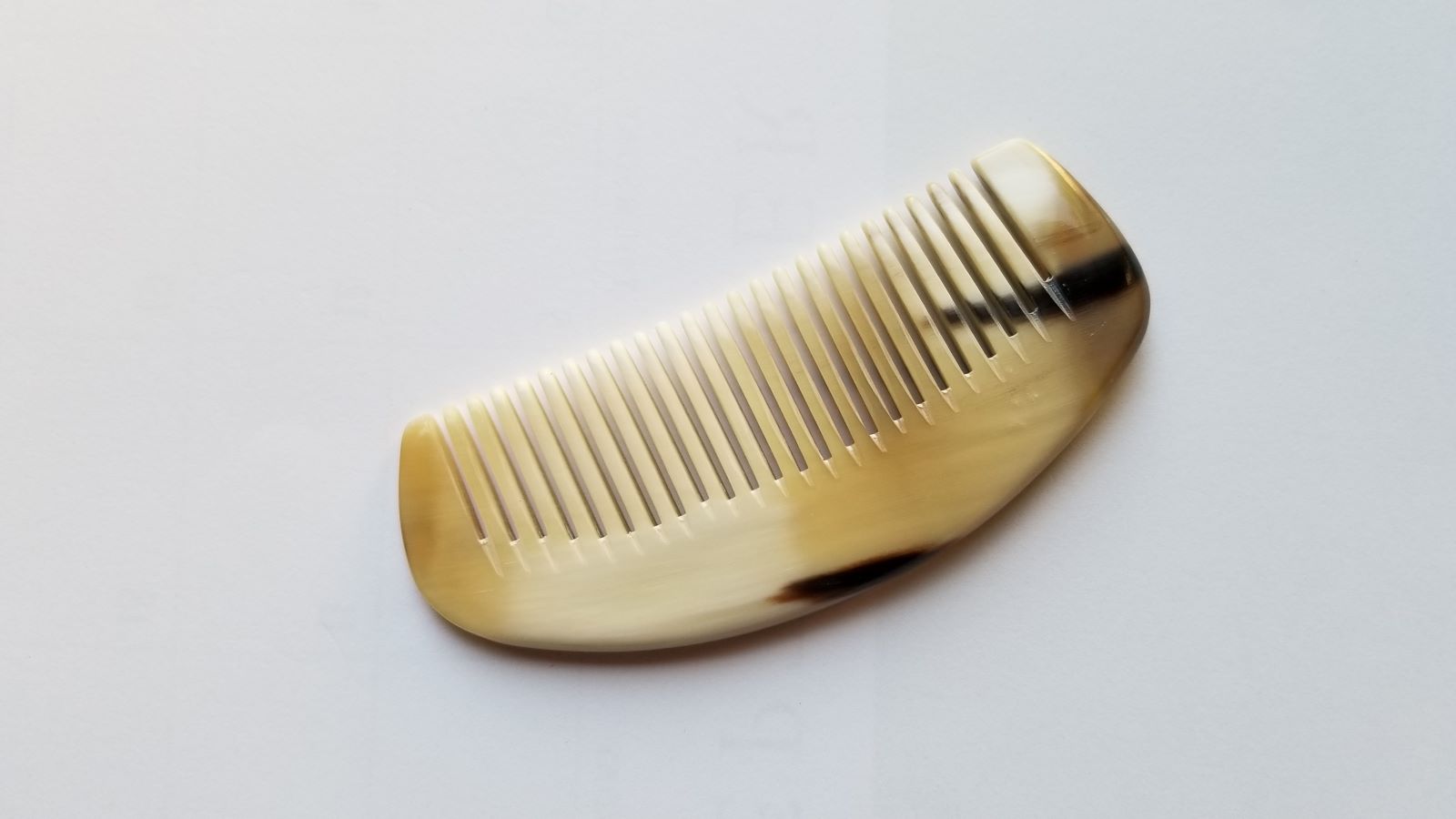 Petite yak horn comb angled view, natural horn grain variation, fine 0.15 cm teeth for fine and straight hair, travel-ready pocket comb