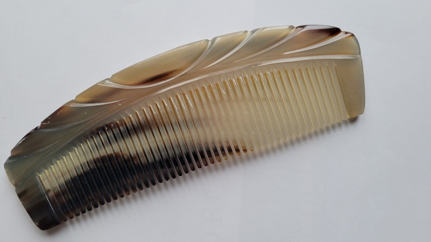 A brown and beige tortoiseshell comb with a curved design. The comb has fine teeth and a smooth, polished finish. Each piece is unique and make it a one of kind gift. 