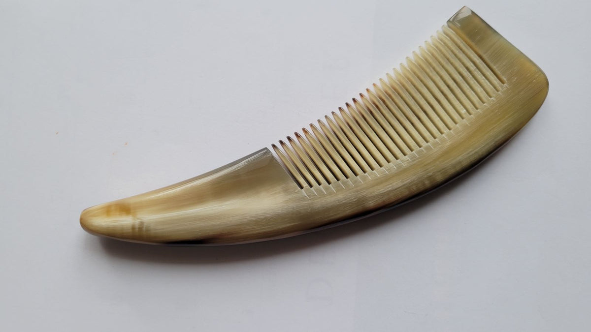 Natural yak horn comb with ergonomic curved handle, warm olive-amber grain, hand-polished fine teeth for snag-free combing
