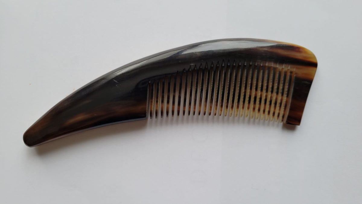 Yak horn comb warm amber-brown color variation, naturally curved handle, keratin-rich horn distributes hair oils for healthy shine