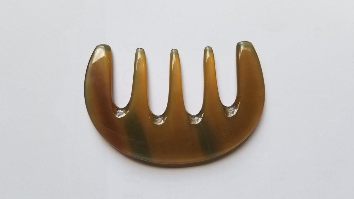 Polished translucent amber yak horn five-tooth comb, flat lay overhead showing natural color variation — Arakicrafts