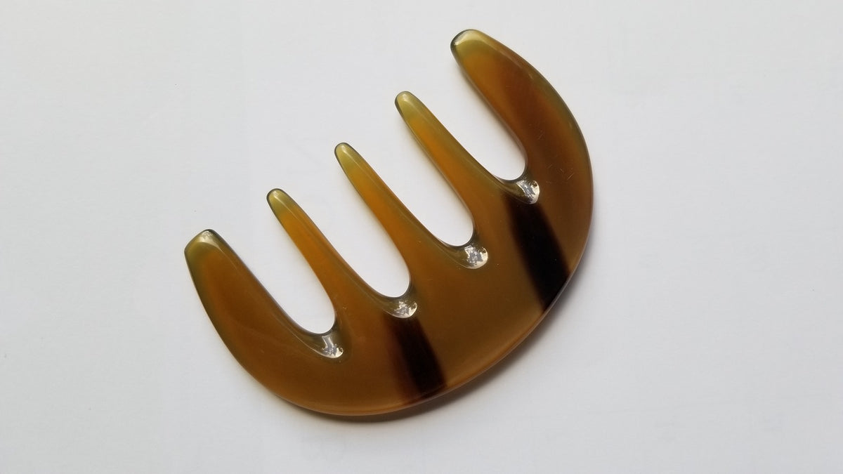A brown, semi-circular comb with five tines and a smooth, polished finish. The comb has a natural, earthy color with subtle variations. The design is simple and functional, suitable for hair care.